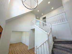 Stairway featuring wood finished floors, a high ceiling, and hanging lights