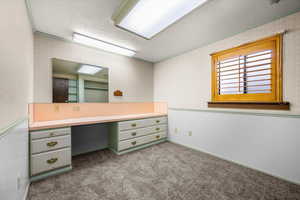 Bathroom with wallpapered walls, crown molding, a textured ceiling, dark carpet, and vanity