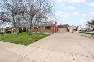 Ranch-style house with brick siding, concrete driveway, a residential view, and a chimney