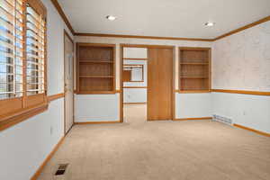 Unfurnished room with built in features, light carpet, ornamental molding, wallpapered walls, and recessed lighting