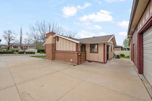 View of side of home featuring board and batten siding, brick siding, a shingled roof, and a chimney