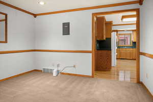 Unfurnished room featuring crown molding, light carpet, and electric panel