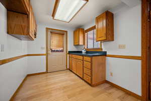 Kitchen featuring wood finish cabinets, light wood-type flooring, and dark countertops