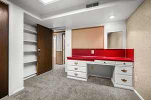 Walk in closet featuring light carpet and built in desk
