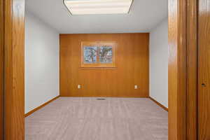 Unfurnished room with wooden walls and light colored carpet