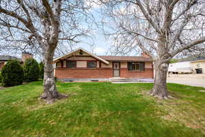 View of front of property with brick siding, a front lawn, and a chimney