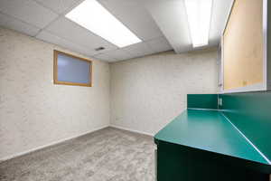 Unfurnished office with a paneled ceiling, wallpapered walls, and light colored carpet