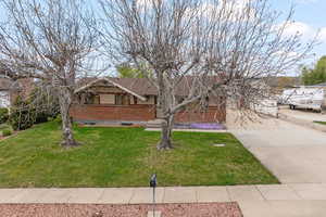 View of front of home featuring a front yard, brick siding, and concrete driveway