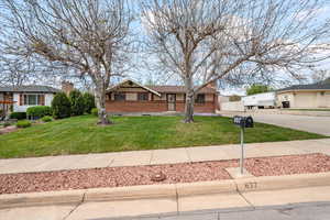View of front of house with brick siding, a front yard, driveway, and a chimney