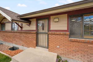 Entrance to property featuring roof with shingles and brick siding