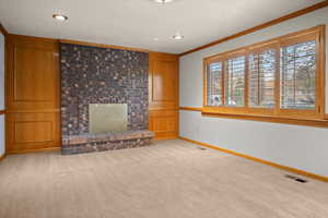 Unfurnished living room featuring light carpet, ornamental molding, and a brick fireplace
