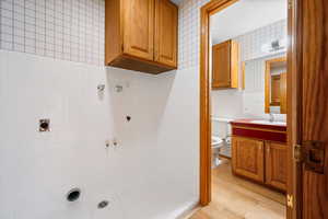 Bathroom featuring vanity, wallpapered walls, light wood finished floors, tile walls, and a tile shower