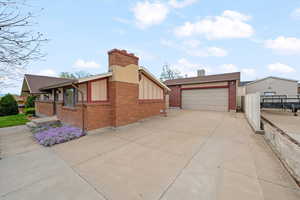 Ranch-style house with brick siding, a chimney, concrete driveway, and board and batten siding