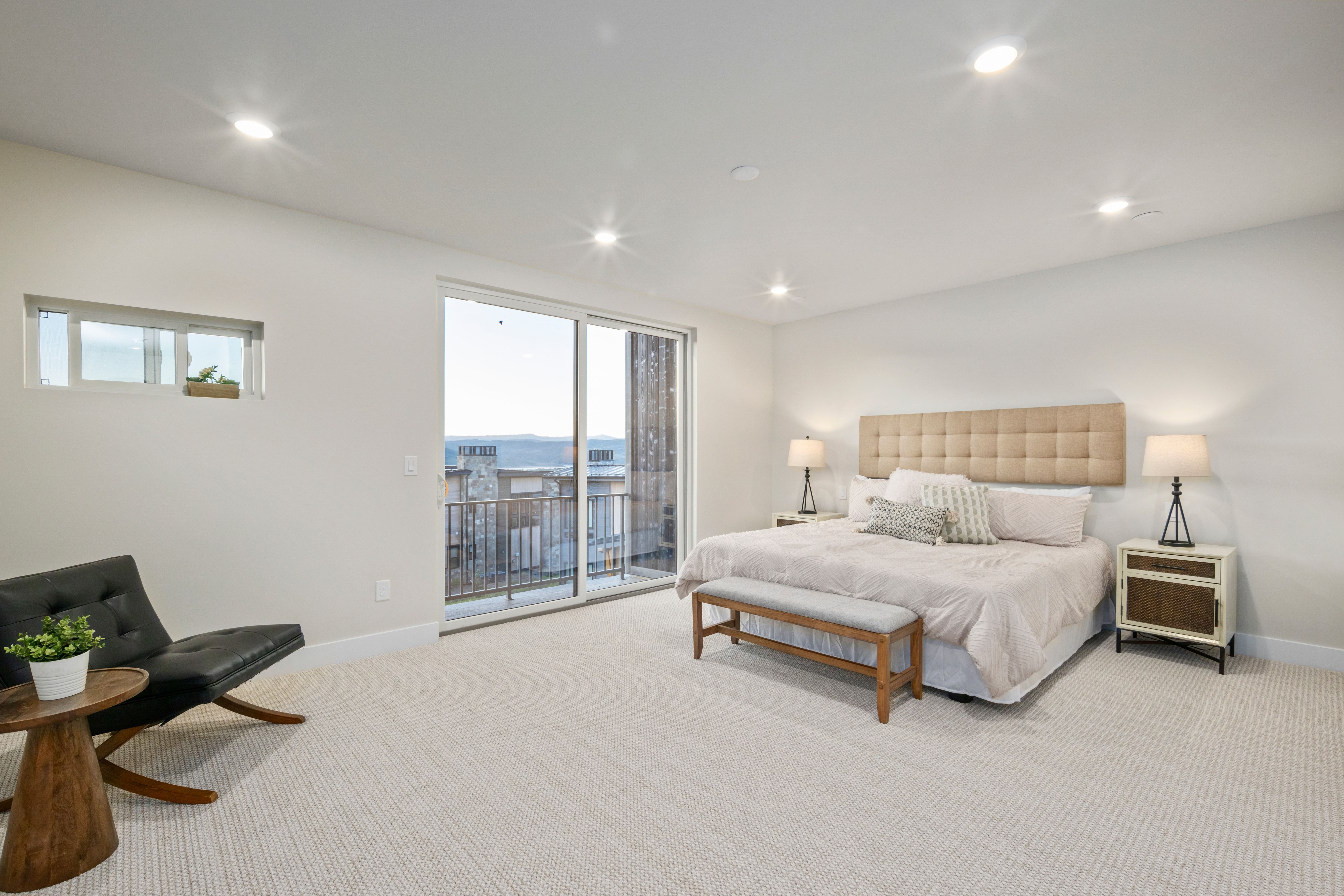 Spacious room featuring a sliding glass door to a balcony, a transom window, recessed ceiling lighting, and light-toned carpeting
