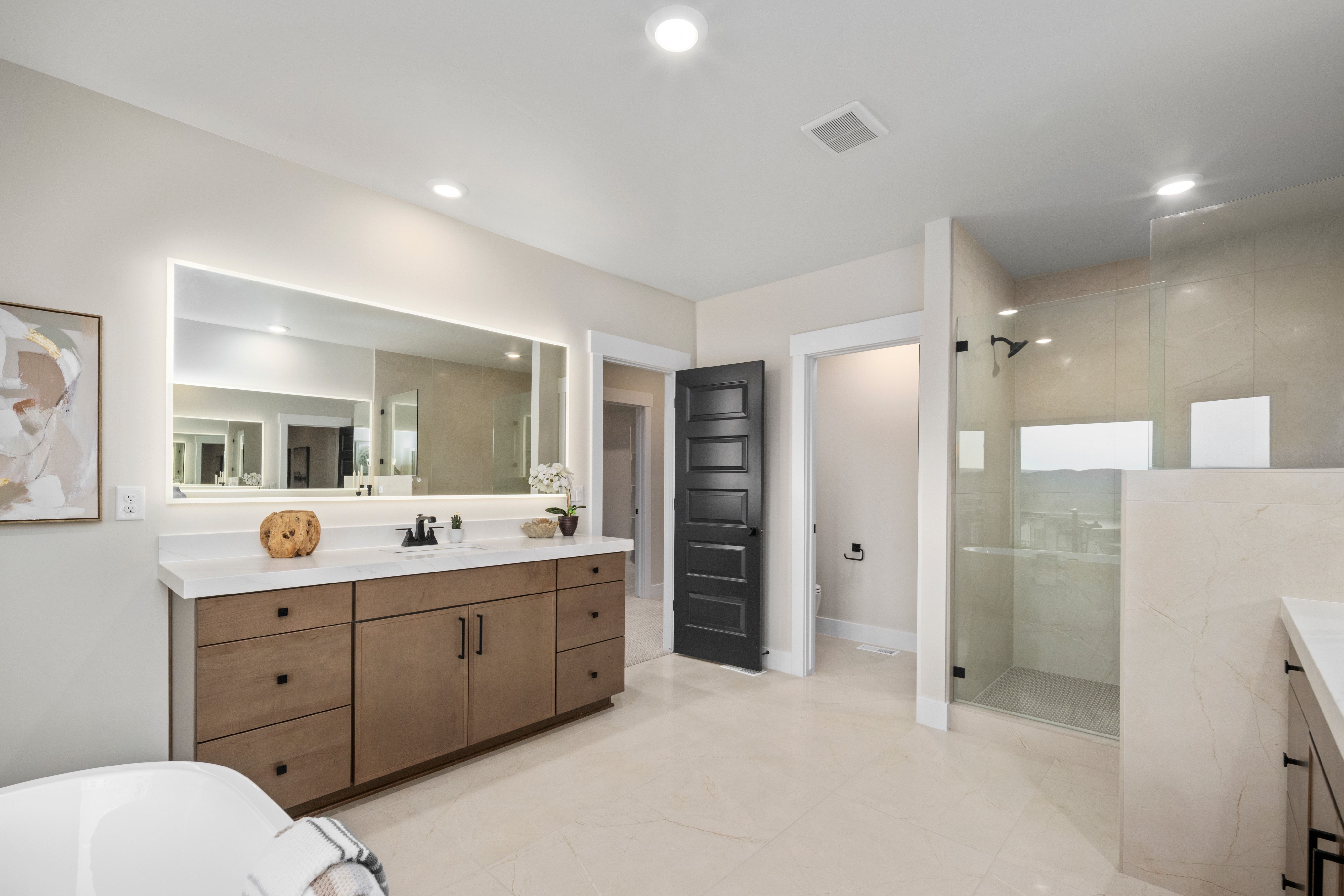 Spacious bathroom featuring a dual vanity with a light-colored countertop and under-mount sinks