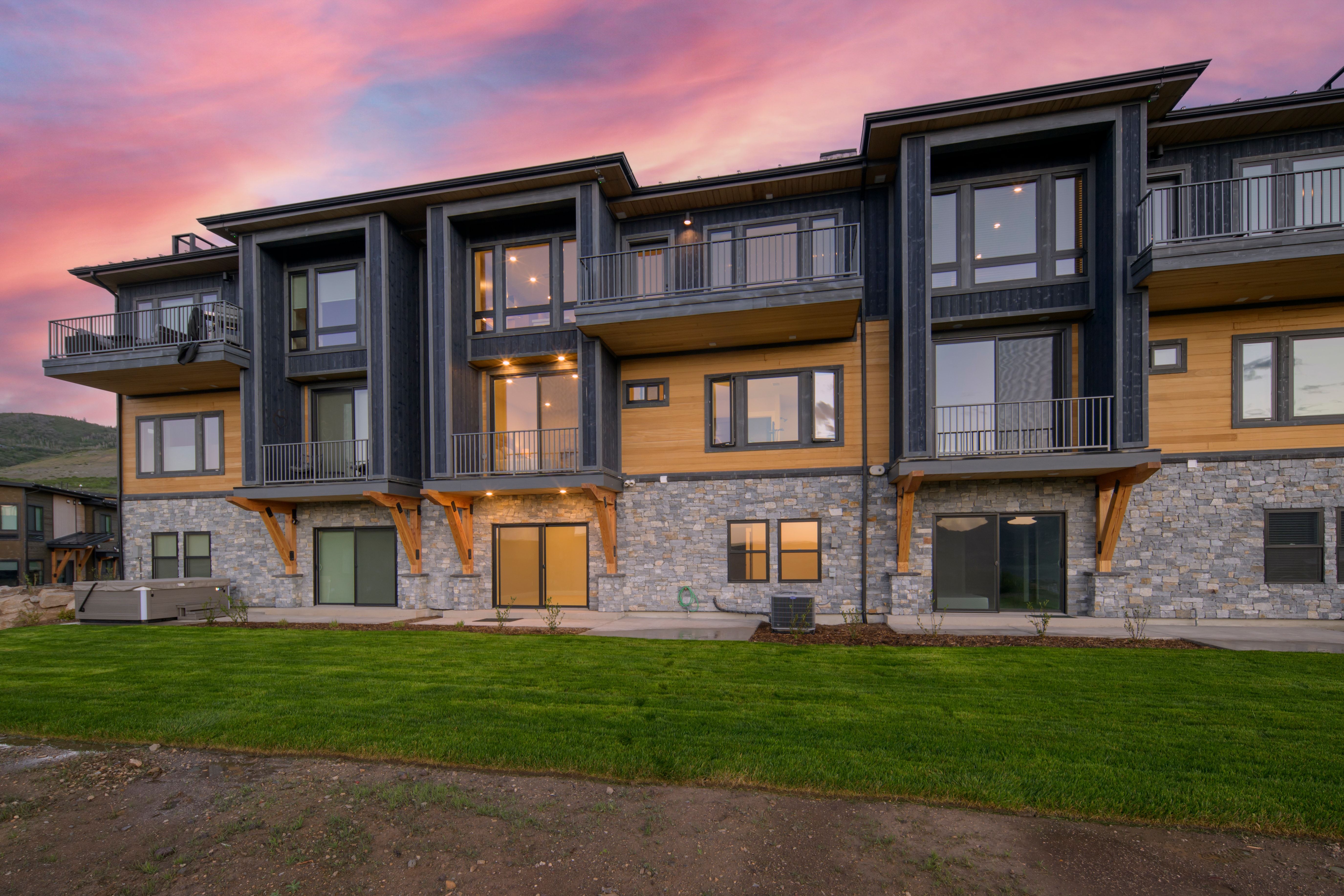 Modern multi-story exterior featuring stone veneer, wood-tone siding, and dark paneling
