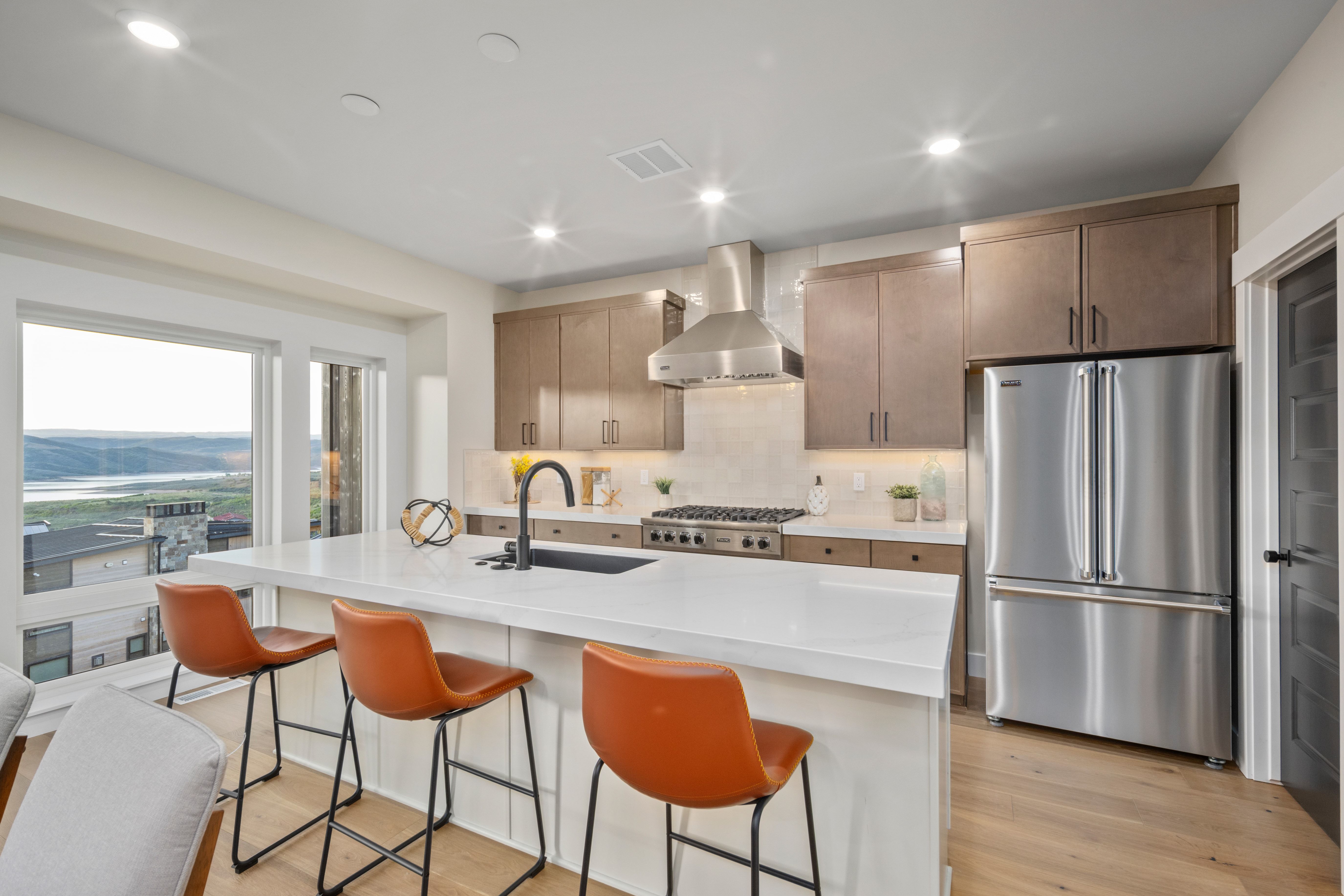Kitchen featuring a large central island with seating, stainless steel appliances, and wood-finish flooring
