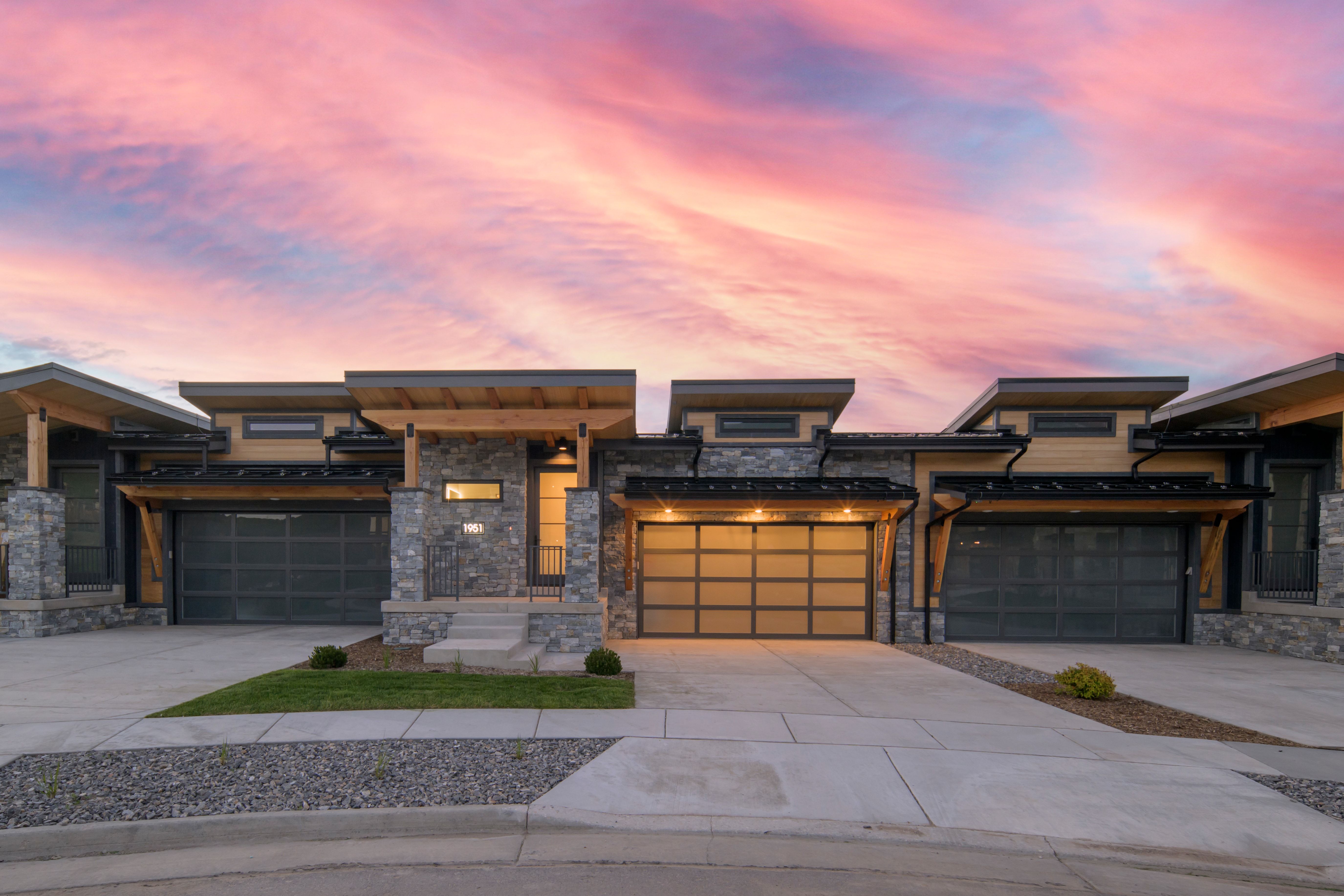 Modern architectural facade featuring stacked stone accents, horizontal siding, and flat rooflines