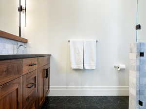 Full bathroom with vanity, tasteful backsplash, and dark tile patterned flooring