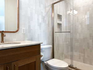 Full bathroom with tile walls, a shower stall, and vanity