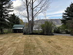 View of green lawn featuring a mountain view and shed