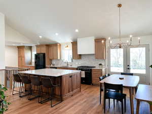 Kitchen with black appliances, wood floors, quartzite countertops, and custom cabinets