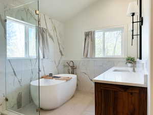 Bathroom featuring a freestanding tub, tile walls, and vaulted ceiling