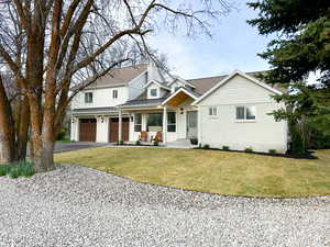 Modern inspired farmhouse featuring asphalt driveway, board and batten siding, a standing seam roof, and a front lawn