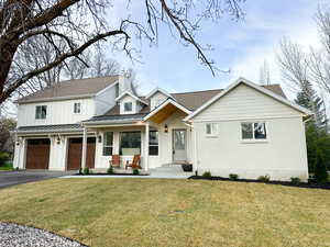 View of front of home featuring a front yard, asphalt driveway, a garage, and a porch