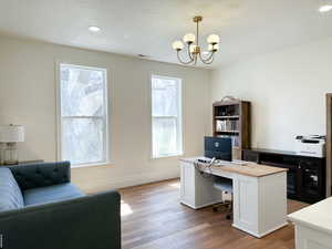 Home office with light wood finished floors, hanging lights, and plenty of natural light
