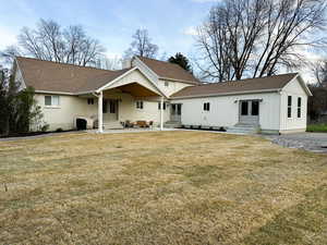 Rear view of property with entry steps, a yard, a patio, and a shingled roof