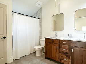 Full bath with double vanity, a shower/tub, and vaulted ceiling