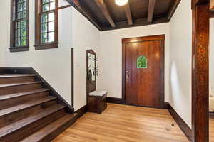 Foyer entrance featuring light wood-type flooring, healthy amount of natural light, and a wooden ceiling with exposed beams