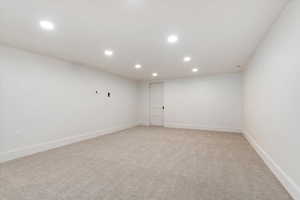 Empty room with light colored carpet and recessed lighting
