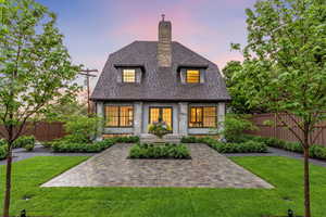 Back of property at dusk with a shingled roof and a chimney