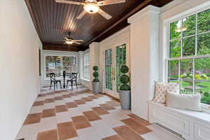 Sunroom / solarium featuring a textured wall, french doors, and wooden ceiling