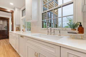 Kitchen featuring white cabinetry, light stone countertops, light wood-style floors, decorative backsplash, and recessed lighting
