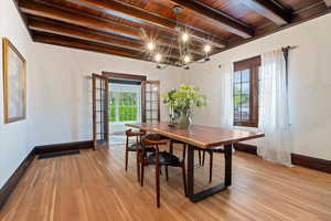 Dining room featuring french doors, light wood-style flooring, suspended lighting, and a wooden ceiling with exposed beams