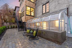 Back of property with a sunroom, a patio, and stucco siding