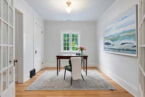 Office with light wood-style floors and ornamental molding