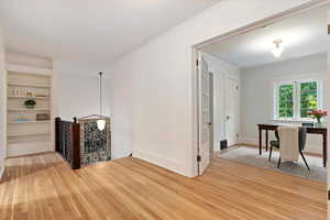 Living area featuring built in features, ornamental molding, and light wood finished floors