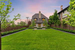 Back of property at dusk featuring a fenced backyard and a chimney