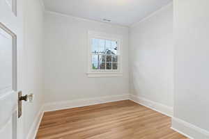 Empty room with light wood-style floors and ornamental molding