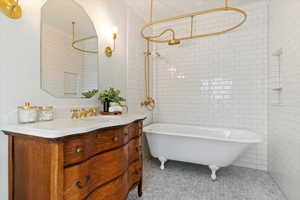 Full bath featuring vanity, tile walls, and a combined bath / shower with freestanding tub