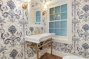Half bath with wallpapered walls and dark wood-style floors