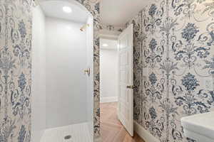 Bathroom featuring a shower stall, parquet floors, wallpapered walls, and recessed lighting