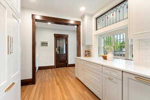 Kitchen featuring backsplash, light wood-style flooring, white cabinets, recessed lighting, and light stone counters