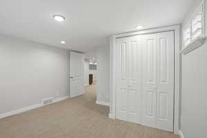 Unfurnished bedroom with a closet, light colored carpet, and recessed lighting