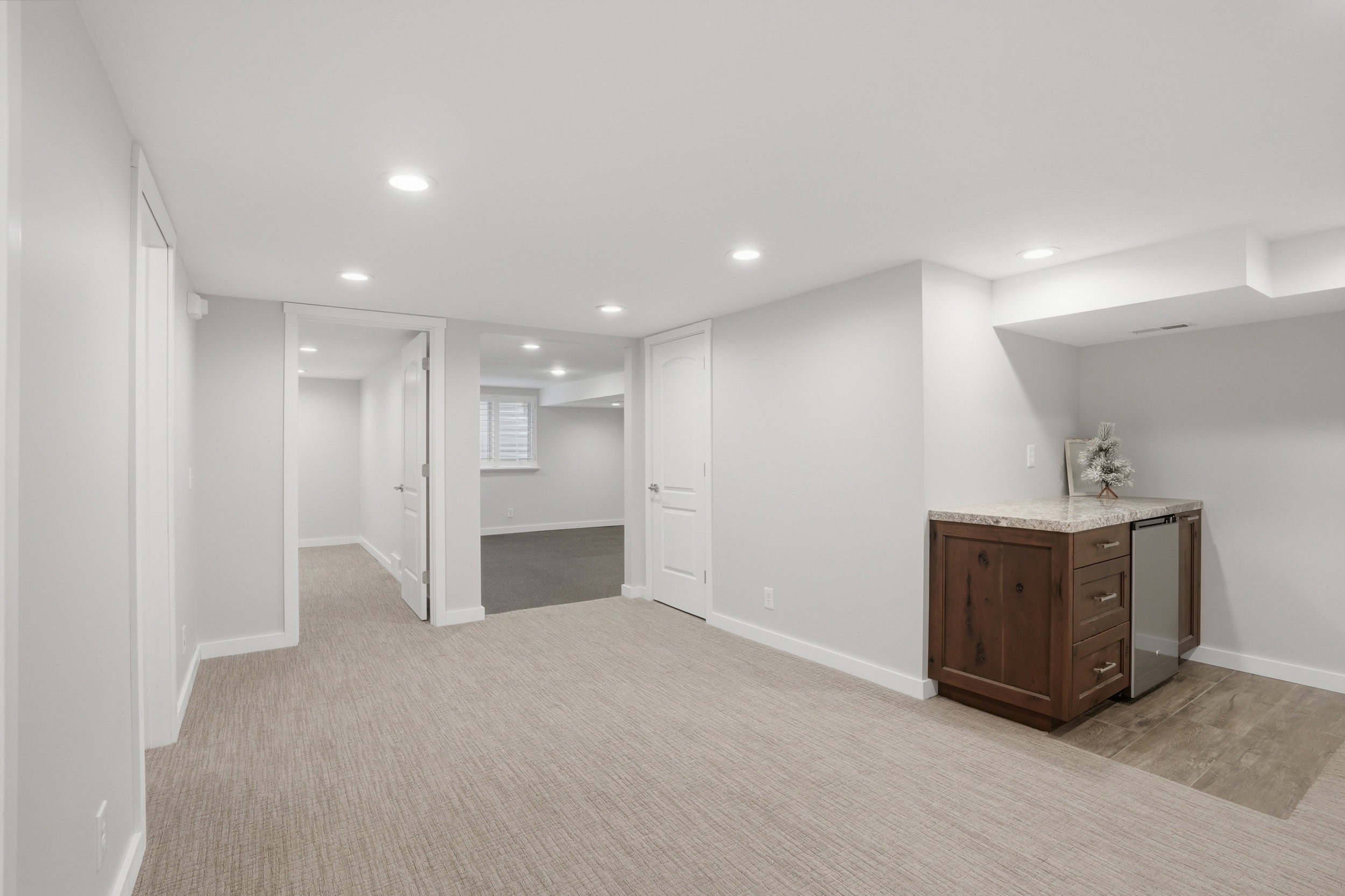 Bar featuring recessed lighting, light stone countertops, dark wood finish cabinetry, stainless steel refrigerator, and light carpet