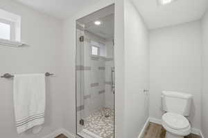 Full bathroom with a shower stall and light wood-style floors